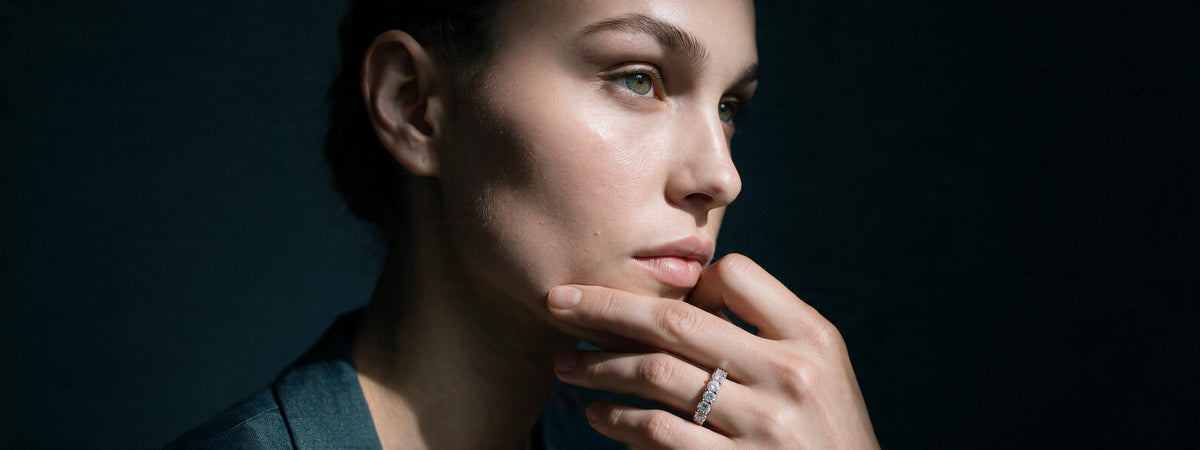Model resting chin on hand displaying a sparkling diamond eternity ring
